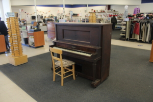A piano sits in the middle of the store.
